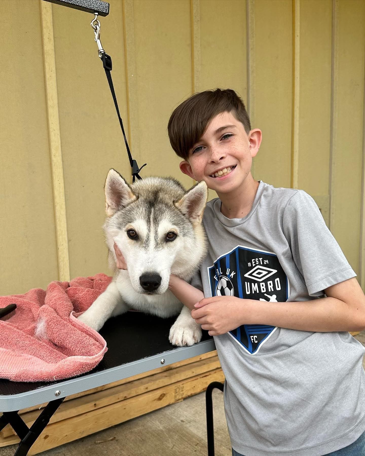 A young volunteer smiling with a Central Texas Husky dog after grooming