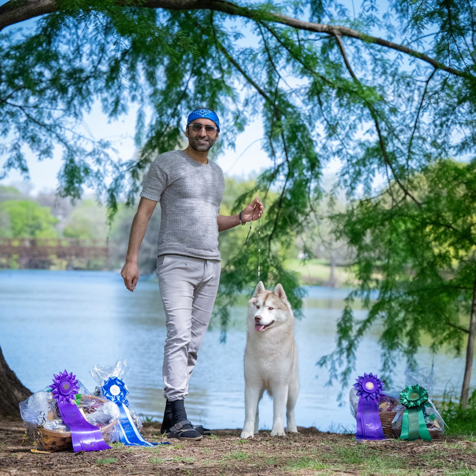 Esteban standing lakeside with his handler and multiple show ribbons