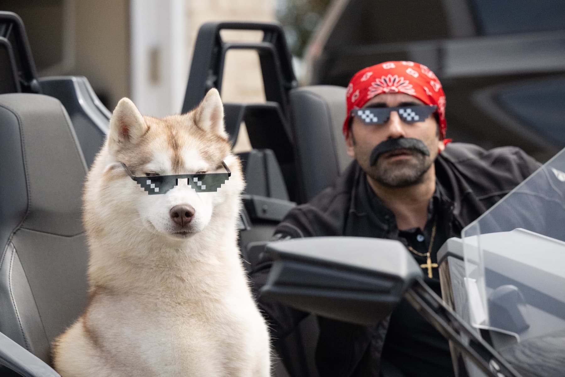 Esteban wearing sunglasses in a convertible with a matching costumed handler behind him