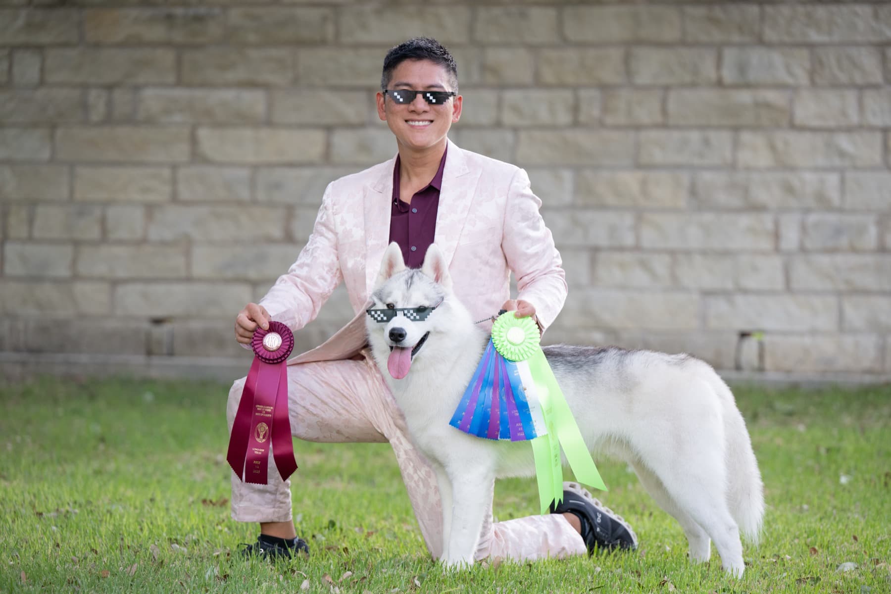 Star wearing sunglasses while posing with ribbons and his handler